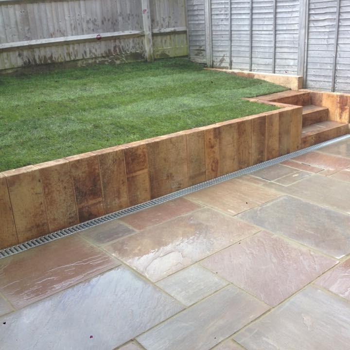 railway oak sleepers bordering fresh turf and sandstone paving