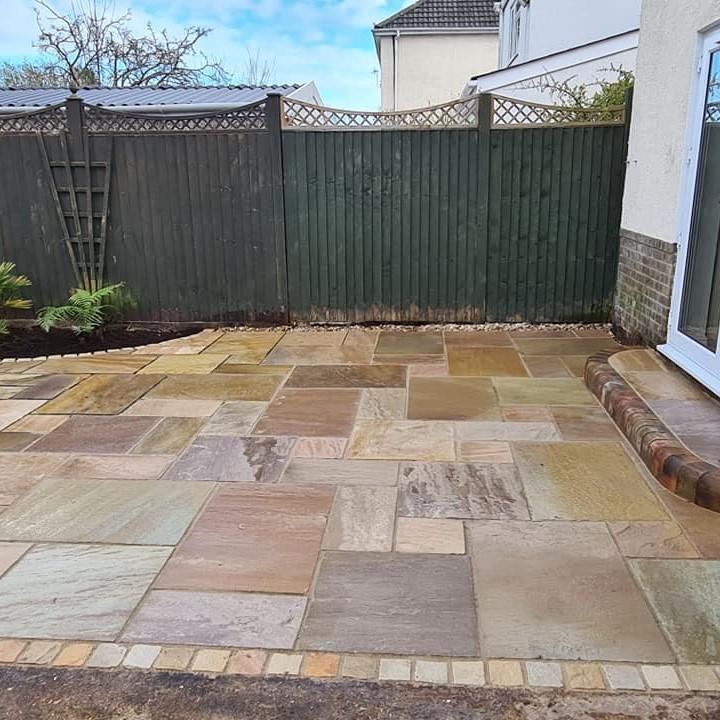garden patio brown paving with green fence