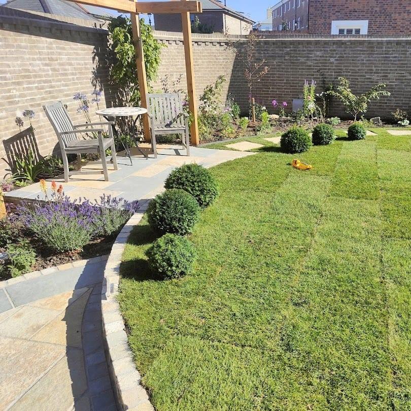 garden with grass area and yellow limestone cobble setts as edging