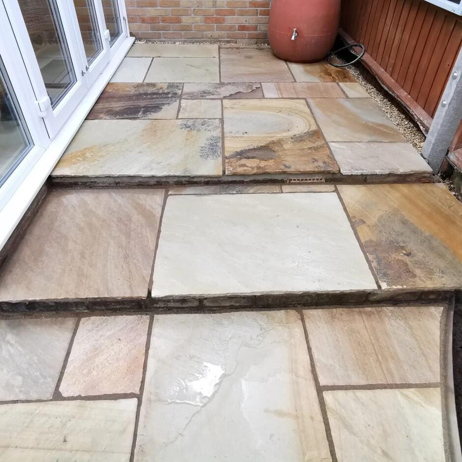 light brown and creame paving slabs patio and back garden with furniture