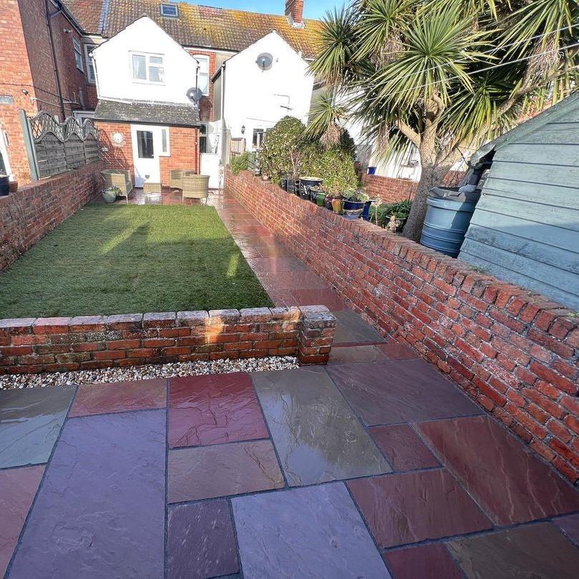 Heather Modak Sandstone Paving with decorative stones and lawn