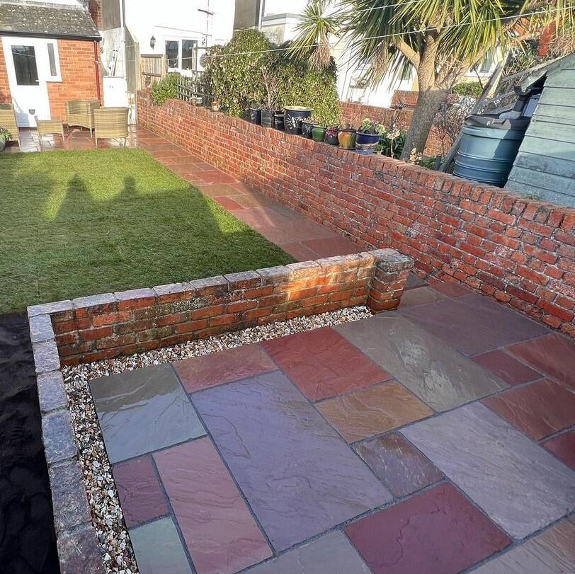 Heather Modak Sandstone Paving back garden with decorative stones and turf