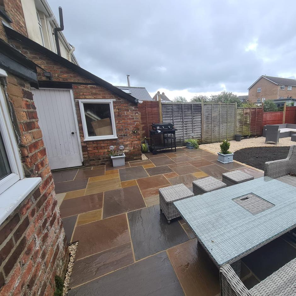 Fernlea Raj Green Sandstone Paving with beige grout brown tan paving slabs with garden loungers soil