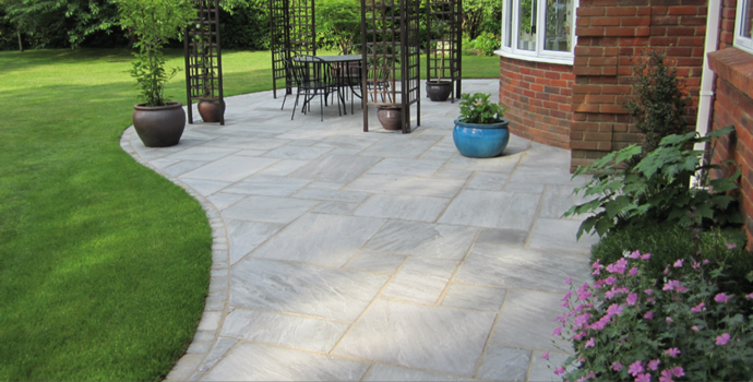 grey paving slabs with pink flowers and turf