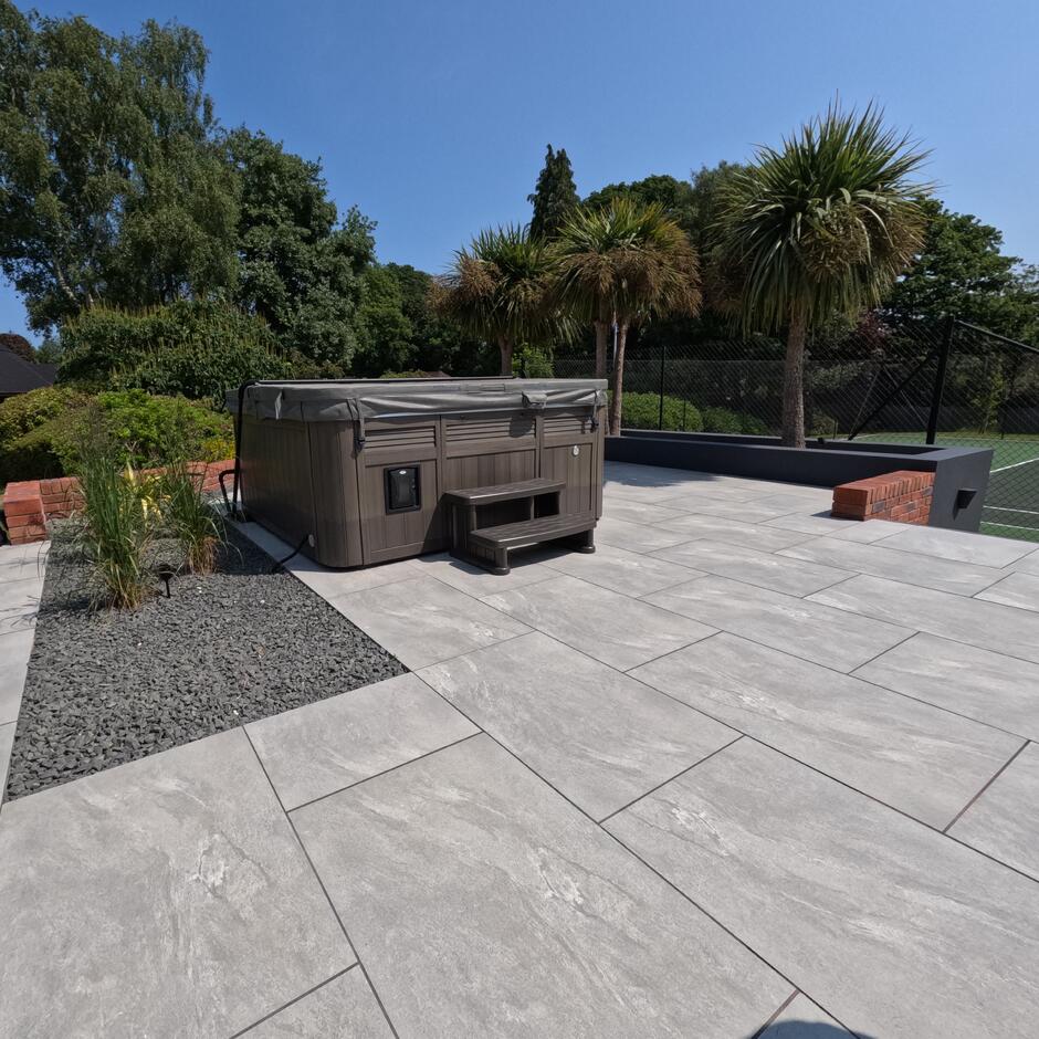 Sienna™ Jupiter Argent Porcelain Paving; grey paving tiles; with dark grey stones and hot tub