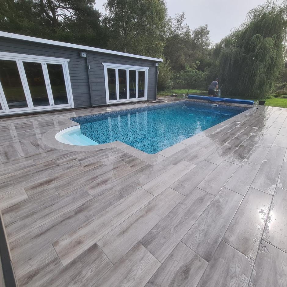 Woodland wood-effect Anthracite Grey Black Porcelain Paving Slab up-close with swimming pool