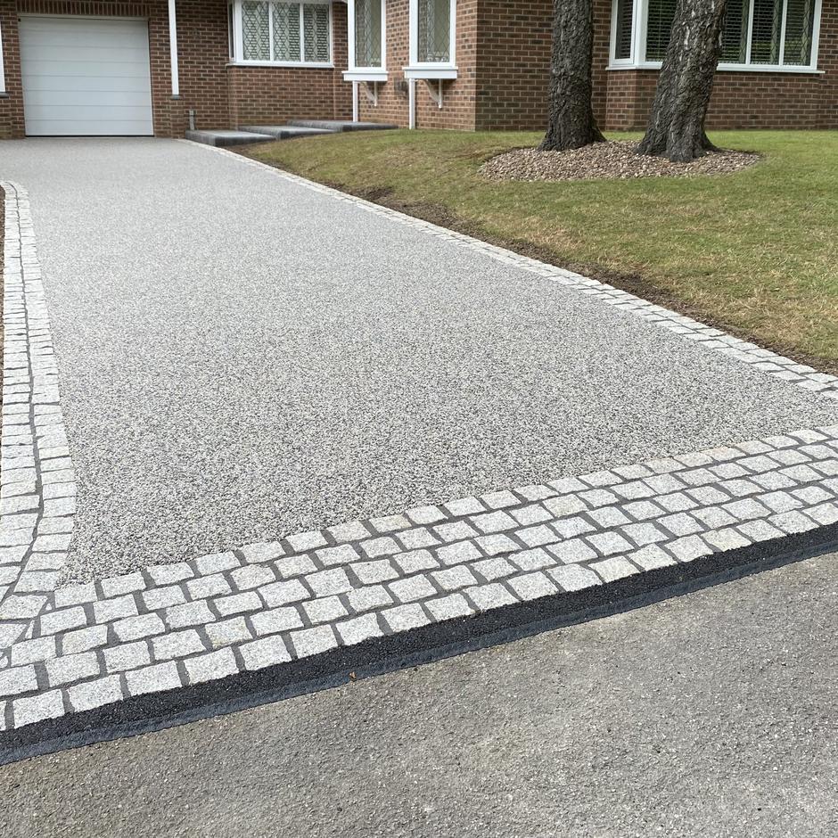 grey resin bound aggregates with grey granite cobble setts as garden edging
